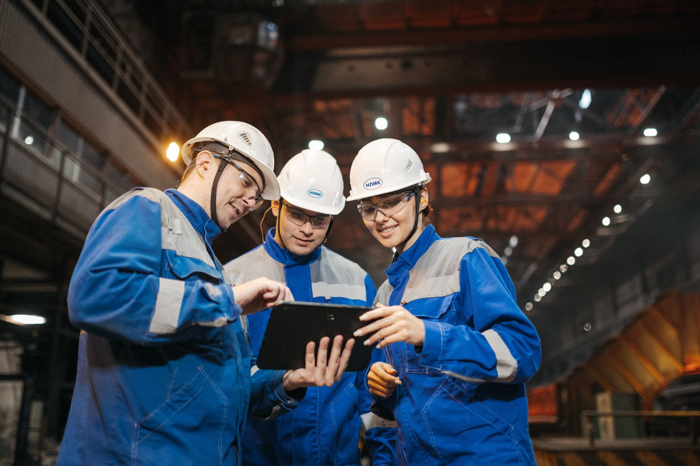 Drie engineers overleggen met een tablet in een industriële productieomgeving